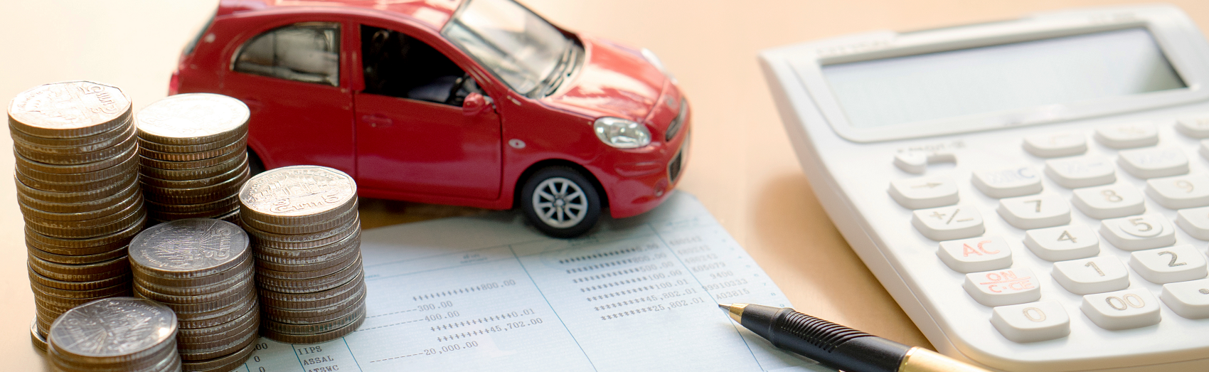 Stack of change sitting next to a toy red car and a calculator