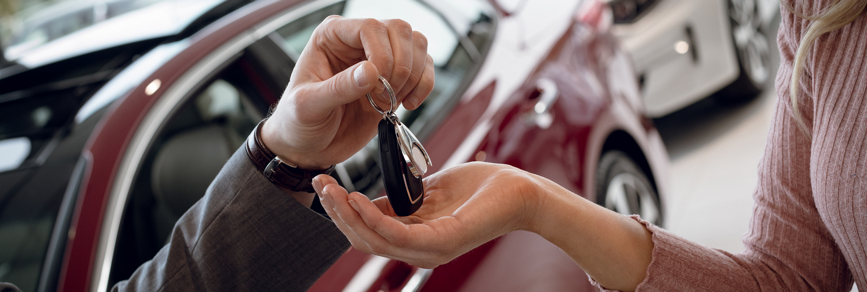 Salesman handing car keys over to woman