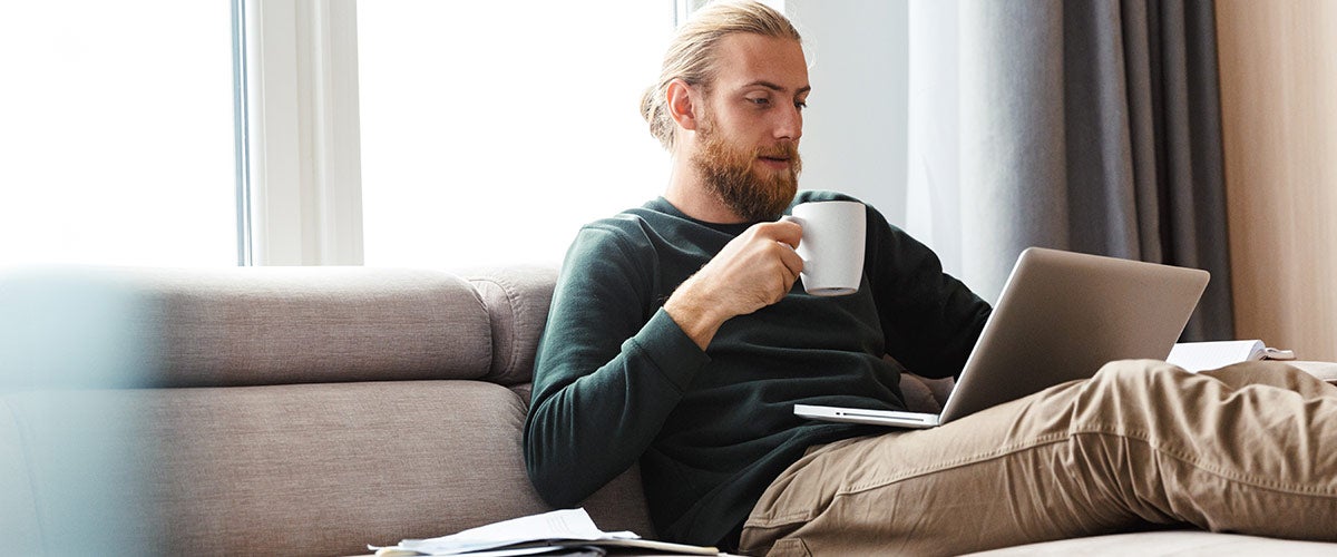 Shopping on laptop while drinking coffee